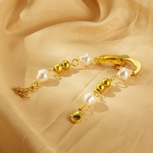Detail of baroque pearl bracelet with gold toggle links on silk champagne background