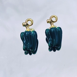 Macro view of green bell pepper alloy enamel charms with gold rings for DIY jewelry