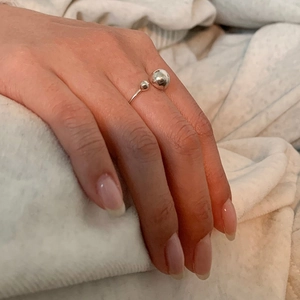 Close-up of S925 sterling silver geometric open ring with dual metal spheres on finger