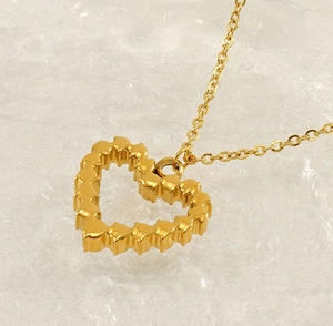Detailed close-up of a gold heart pendant necklace with textured wavy edges on white crystal
