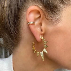 Close-up of gold spike hoop earrings and ear cuff with micro-pave crystals on female ear