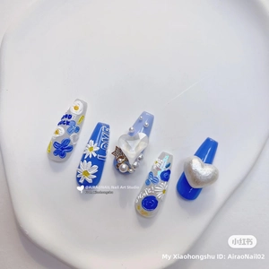 Detail of 5D embossed press-on nails with 3D floral patterns and blue heart accents