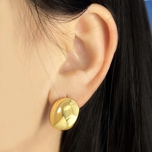 Close-up of elegant gold bean shaped stud earrings with a polished mirror finish on model