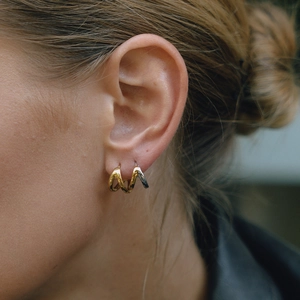Close-up of wavy 18K gold and stainless steel bicolor hollow earrings on female model