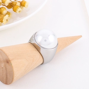 Bague large en acier inoxydable poli avec grande perle blanche sur support en bois
