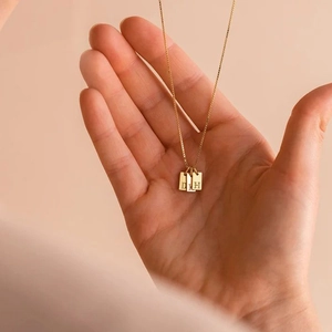 Close-up of golden box chain with three vertical rectangular letter pendants D, L, H
