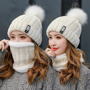 Creamy white knit beanie with faux fur pom and thick plush-lined scarf for winter warmth
