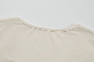 Detail of round neckline with reinforced double-needle stitching on cream knit top