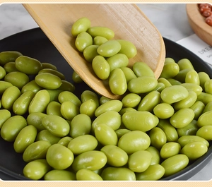 Detailed macro view of artificial green edamame beans in black plate with wooden scoop