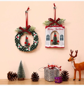 Detail of round Christmas wreath and house shaped wooden hanging decor with plaid bow