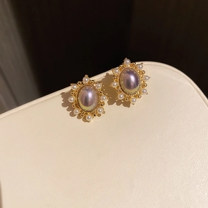 Macro detail of vintage gold oval pearl earrings with small white pearl halo surround