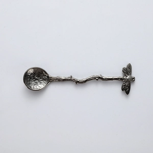 Detailed view of dragonfly handle design and hammered texture on metal dessert spoon