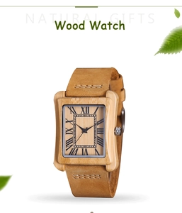 Detail of wooden watch with Roman numerals on wood dial and green leaf accents