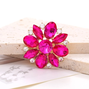 Detail shot of rose red crystal flower accessory with gold base on a textured stone surface