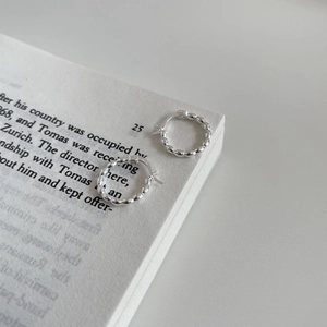 Macro shot of S925 sterling silver beaded hoop earrings placed on minimalist book pages