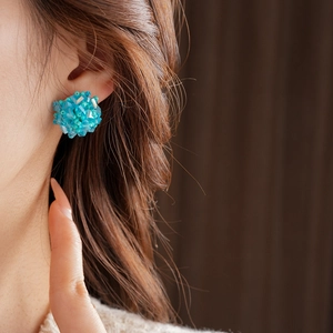 Close-up of a blue bead flower cluster earring worn on ear with professional focus