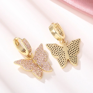 Close-up of gold butterfly earrings featuring micro-set pink zircons and hoop closures