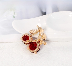 Macro detail of a golden cherry brooch featuring two faceted red crystal gemstones