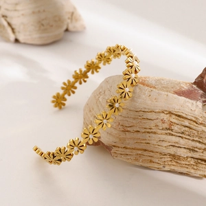 Detail of 18k gold plated daisy bangle with pearls and crystals on a natural stone base