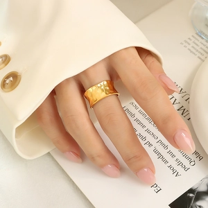 Golden wide hammered metal ring with minimalist irregular textured finish on a model