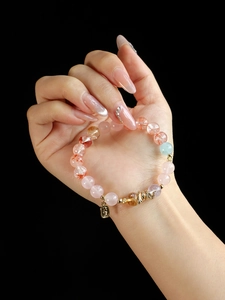 Detailed close-up of pink crystal bead bracelet with a lucky gold metal pendant charm