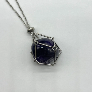 Macro view of purple spherical gemstone pendant in silver-tone stainless steel mesh cage