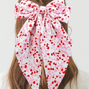 White ribbon bow hair clip with red heart prints worn on long hair for Valentine's Day