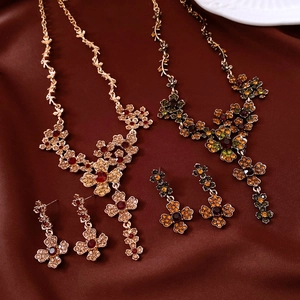 Detail of luxury flower pendants with red and green gemstones on silk background