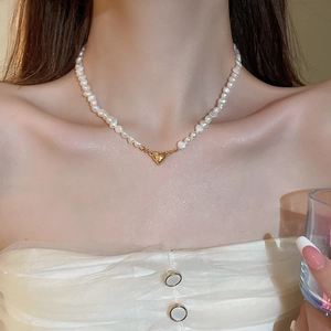 Detail of 18K gold heart pendant and lustrous freshwater pearls on model neck
