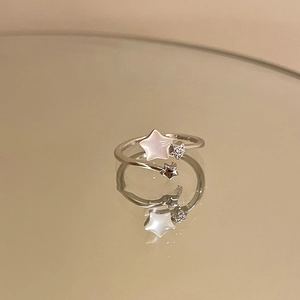 Detail of adjustable star ring with zircon and shell inlay on reflective mirror surface