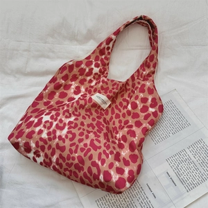 Detailed view of leopard print canvas tote bag with woven brand label and reinforced straps