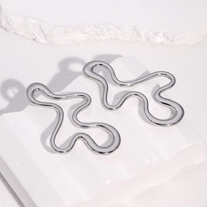 Irregular silver stainless steel stud earrings displayed on a white textured stone base