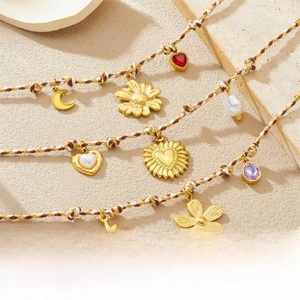 Detail of bohemian woven bracelets with gold sun, moon, and heart charms on stone