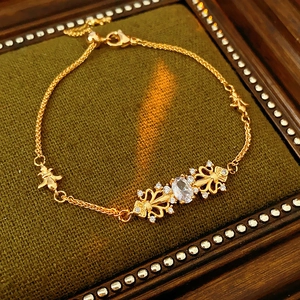 Dettaglio del bracciale iris dorato con zirconi su uno sfondo verde testurizzato
