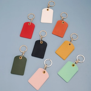 Nine colorful square faux leather access card keychains with gold metal rings on blue