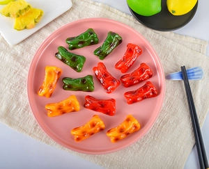 Artistic roasted bell pepper chopstick rests in red green and yellow on a pink plate