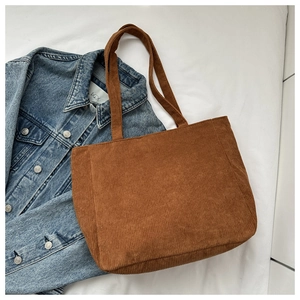 Flat lay of brown corduroy tote bag showing soft ribbed texture on white fabric
