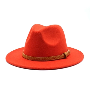 Detail of red wool felt fedora hat featuring a brown snakeskin texture leather belt