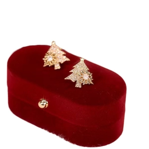 Sparkling gold Christmas tree stud earrings with zircons on a red velvet jewelry box