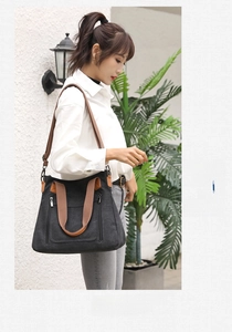 Detail of black canvas tote bag with brown straps and zipper pocket on model