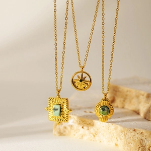 Vintage gold necklaces with turquoise pendants displayed on a natural stone background