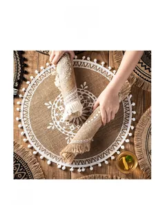 Detail of hand-woven jute placemat with white floral pattern and soft pom-pom fringe