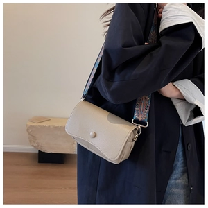 Detail of beige lychee grain faux leather crossbody bag with ethnic pattern wide strap