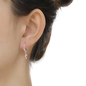 Detailed view of an S999 sterling silver earring with a small dolphin pendant on a model