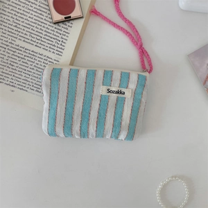 Detailed macro view of striped canvas pouch with pink rope handle and brand label