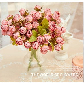 Retro artificial rose bouquet in a ribbed glass vase with elegant candle decor