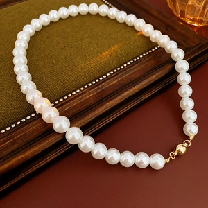 Close-up of vintage pearl necklace featuring a golden magnetic clasp on a retro frame