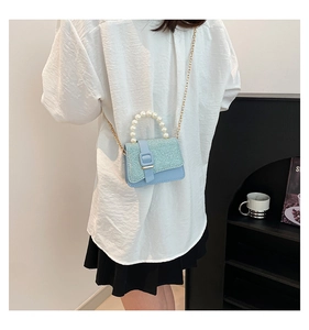 Detail of light blue sequin mini bag with pearl handle and golden chain strap