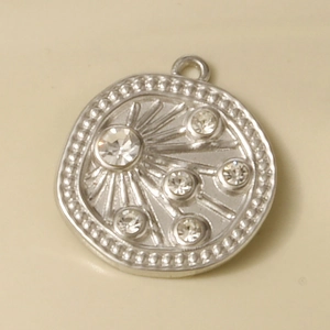 Macro shot of silver irregular round pendant with relief lines and sparkling rhinestones