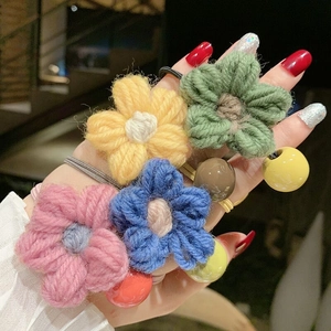 Esposizione al polso di quattro elastici per capelli a fiore in maglia con perline